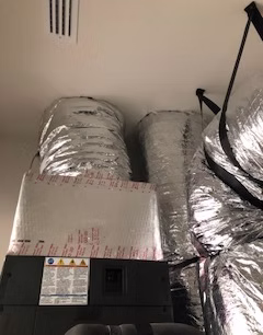 Residential HVAC insulated ductwork connected to air handler in attic space