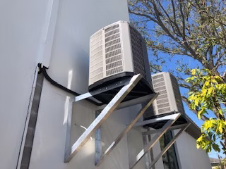 Residential ductless mini split AC units installed on exterior wall brackets